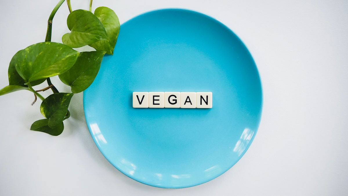Illustrative stock photograph showing a plate with a small plant and scrabble tiles spelling vegan
